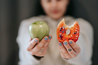 Person håller i äpple och munk